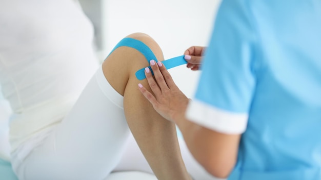 Physiotherapist put kinesiology tape on clients knee remove pain rehabilitation center