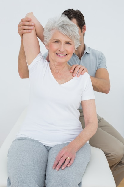 Physiotherapist stretching a smiling senior womans arm