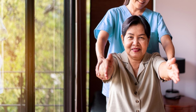 Physiotherapist training with elderly asian woman patient at home Physical therapy concept