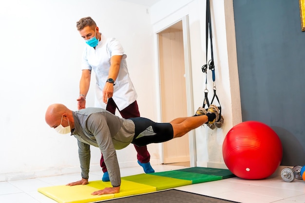 Physiotherapist with mask measuring the temperature to a patient Physiotherapy with protective measures for the Coronavirus pandemic COVID19 Osteopathy sports quiromassage