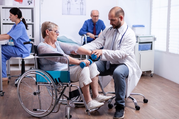 Physiotherapy for elderly woman in wheelchair to regain muscle strength in recovery clinic