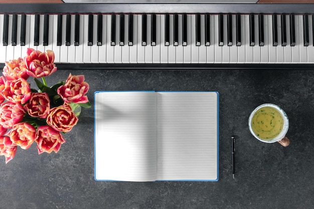 Piano bouquet of spring flowers notepad and cup of tea on a dark background