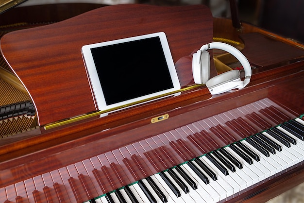 On the piano is a sign with an empty field and white headphones Music festival