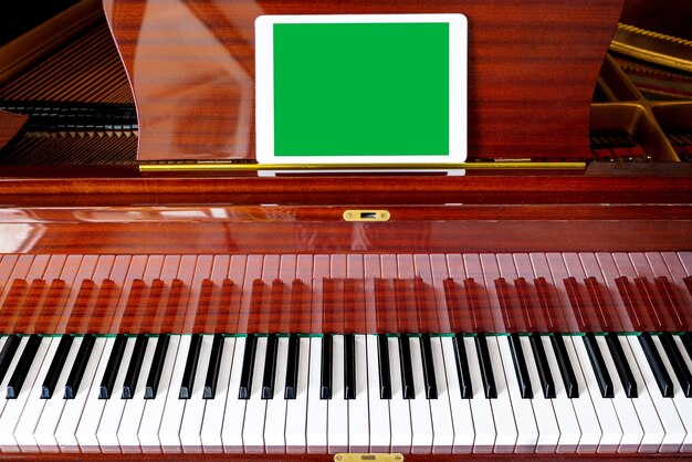 On the piano there is a tablet with an empty field chroma key Music festival mockup