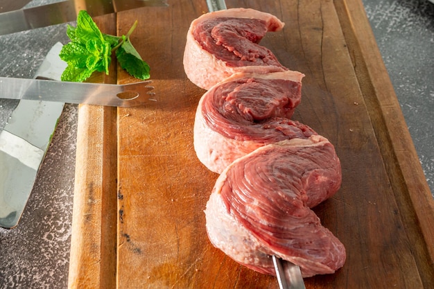 Picanha skewer with three steaks on cutting board