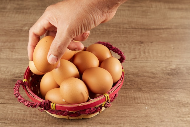 Piciking fresh eggs from a wicker basket on a table