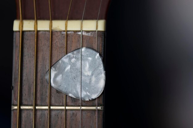 Photo pick between acoustic guitar strings