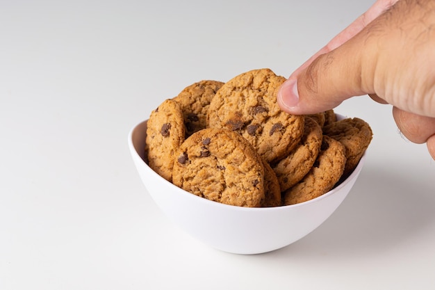 Picking up cookies from white bowl on white background isolated