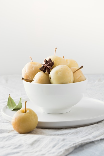 Pickled apples in bowl on white stone table.