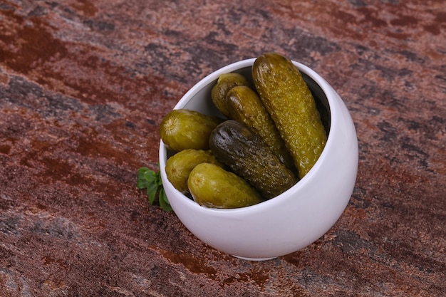 Pickled cucumbers heap in the bowl served basil leaves