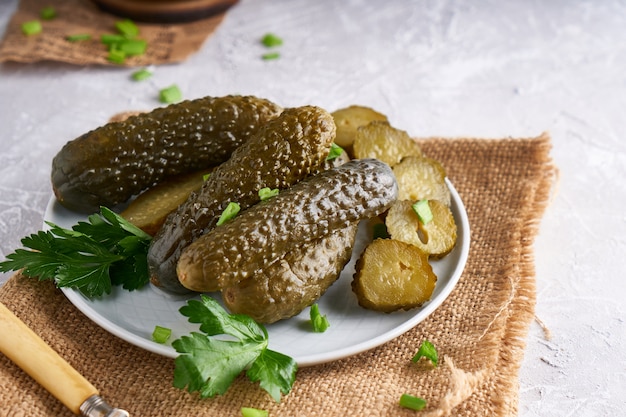 Pickled cucumbers with herbs and onions in a plate on the table Probiotics food