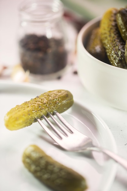 Pickled gherkin on a fork, salted cucumber on a plate