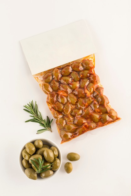 Pickled olives with paprika spices in a vacuum package with a place for the label on a light background. Top view with a copy space for text. Vertical orientation.