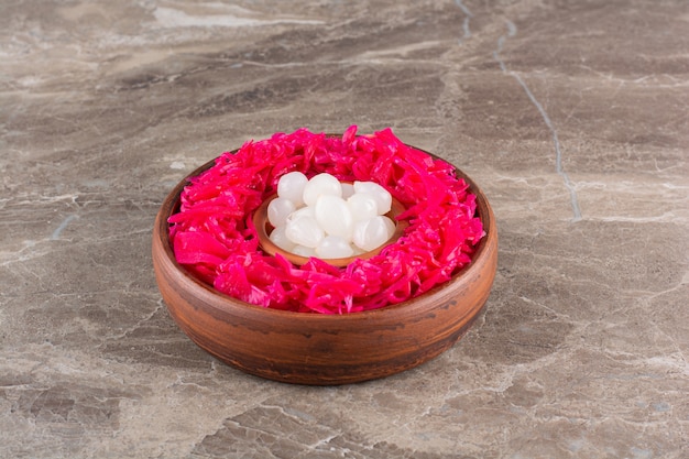 Pickled red cabbage with cloves of garlic placed on stone table.