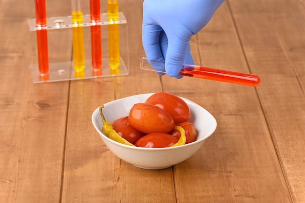 Pickled red tomatoes with chilli and laboratory glass with red liquid.