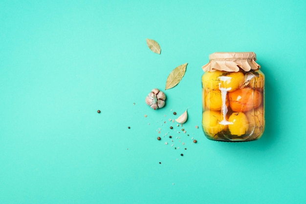 Photo pickled tomatoes in jar on blue background top view flat lay copy space canned and preserved vegetables ingredients for vegetables preserving healthy fermented food concept