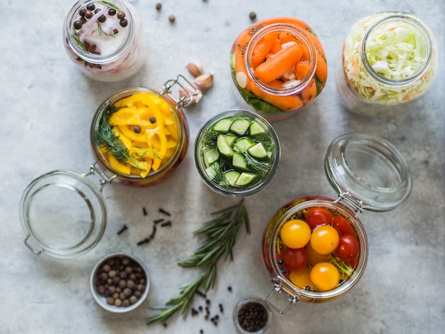 Pickled vegetables. Salting various vegetables in glass jars for long-term storage. Preserves vegetables in glass jars. Variety fermented green vegetables on table. Top view.