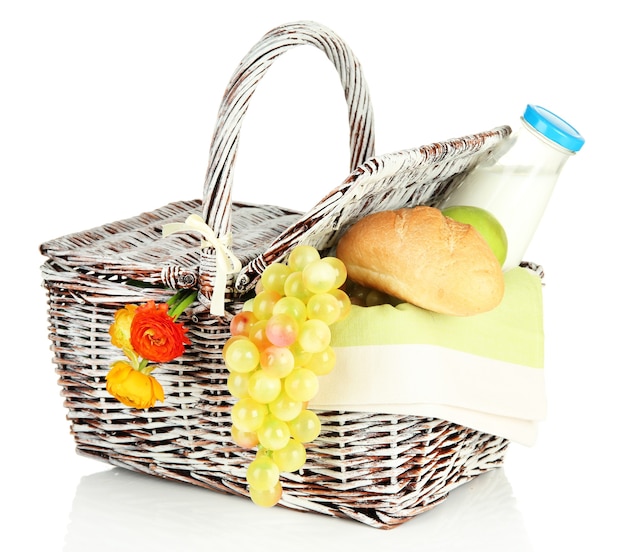 Picnic basket with fruits and bottle of milk, on white