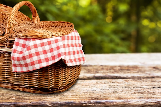 Picnic basket with a tablecloth on a wooden table