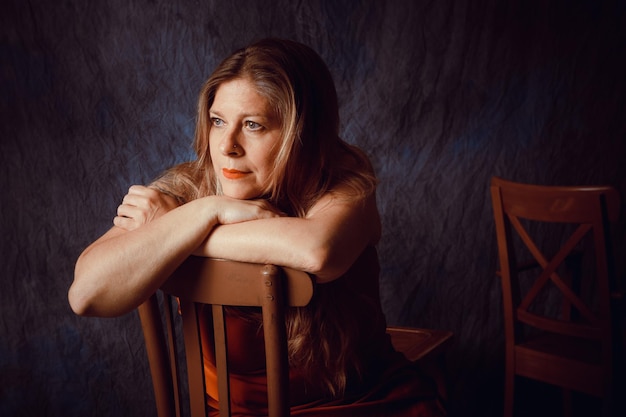 Pictorial portrait of pensive middle-aged woman sitting in an old chair