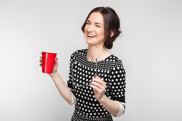 Picture of attractive woman in speckled clothes standing with cup in hands