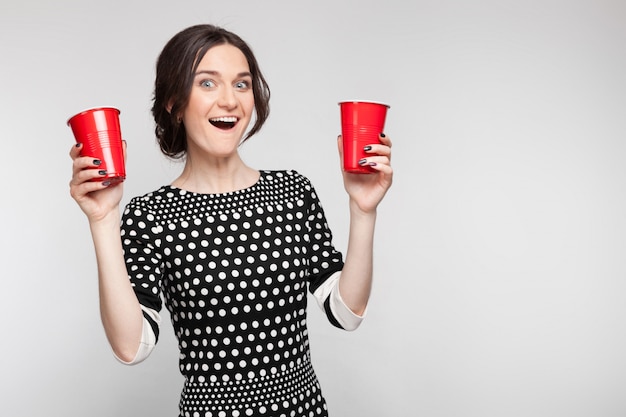 Picture of attractive woman in speckled clothes standing with cup in hands