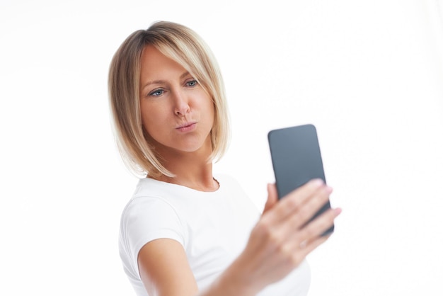 Picture of blonde woman over back isolated background with mobile phone