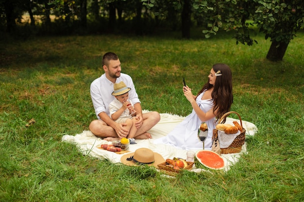 Picture of cheerful young caucasian female and male holds their child on hands, smiles and rejoices