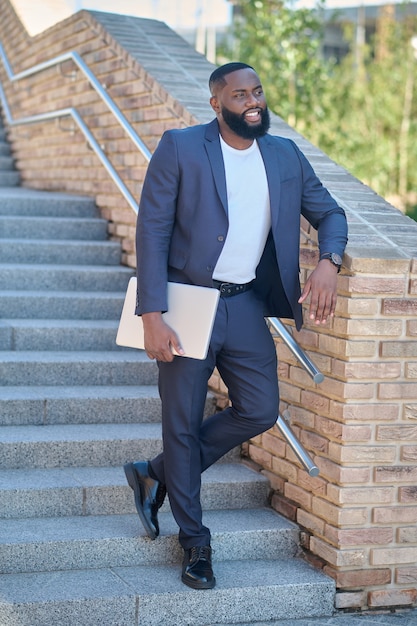 A picture of a dark-skinned man in a suit with a laptop