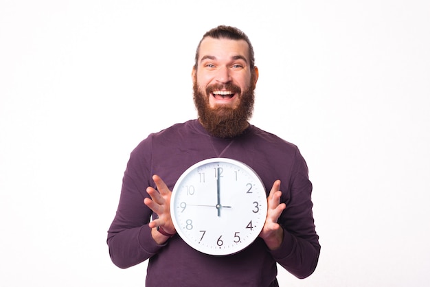 Picture of an excited man holding a clock is smiling