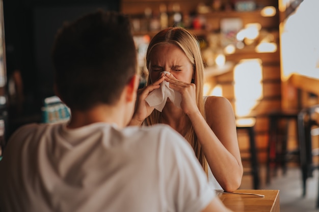 Picture from a young woman with handkerchief. Sick girl isolated has runny nose. Female model makes a cure for the common cold