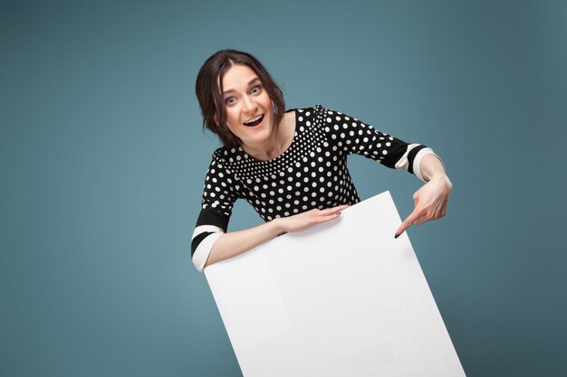 Photo picture of good looking woman in speckled clothes standing with big blank placard in hands