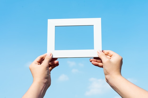 Picture of hands holding photo frames on blue sky background