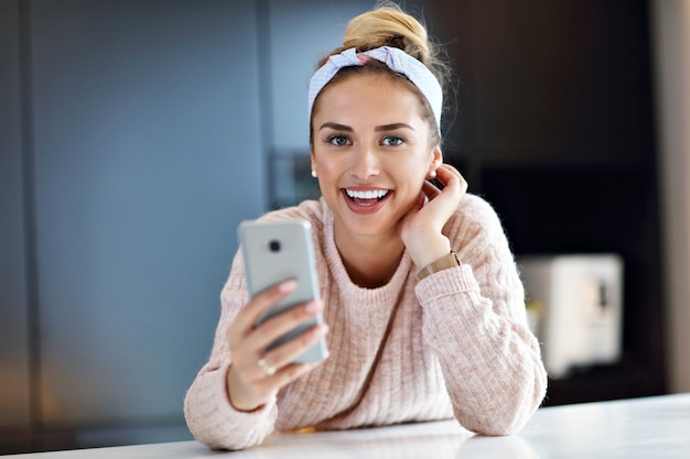 Picture of happy woman texting in the kitchen