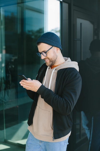 Picture of happy young man holding his cellphone in hands and chatting