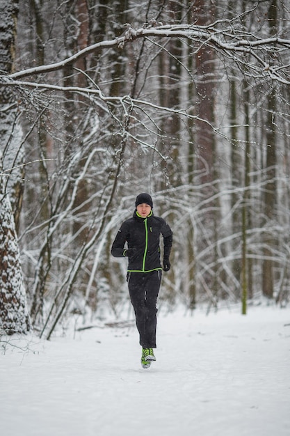 Picture of man in sportswear black hat jogging in winter