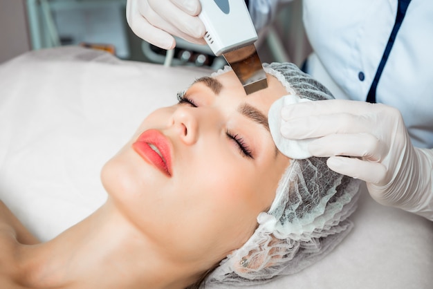 Picture of nice beautician doing oxygen therapy for young woman laying