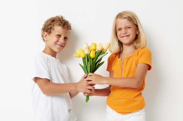 Picture of positive boy and girl holiday friendship with a gift Yellow flowers light background