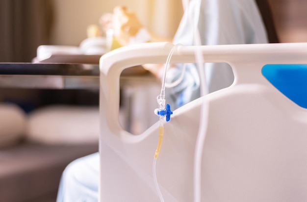 Picture of saline intravenous or iv solution on sickbed with blured patient in hospital