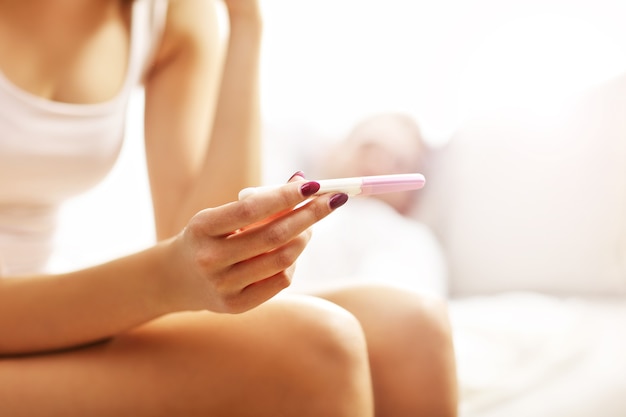 Picture showing woman with pregnancy test in bedroom