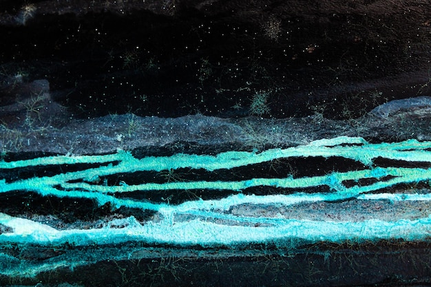 A picture of a turquoise sea at the foot of blue mountains in a black sky with stars