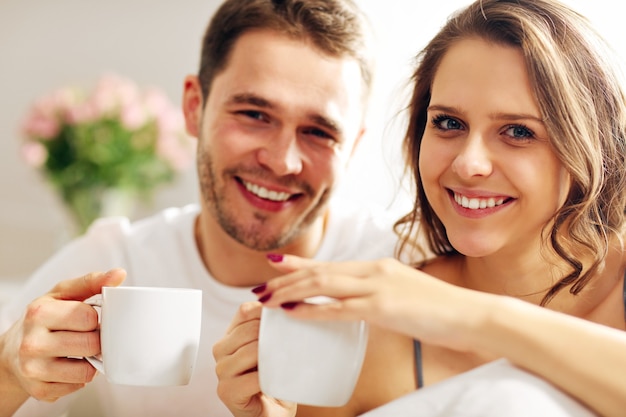 Picture of young couple drinking coffee in bed