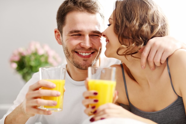 Photo picture of young couple eating breakfast in bed