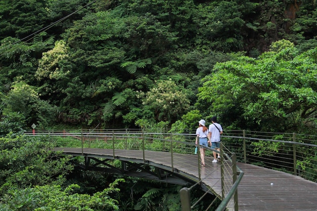 Picture of young couple wearing white t-shirt are standing on wooden bridge walkway. Jiufen-Jinguashi , Taiwan