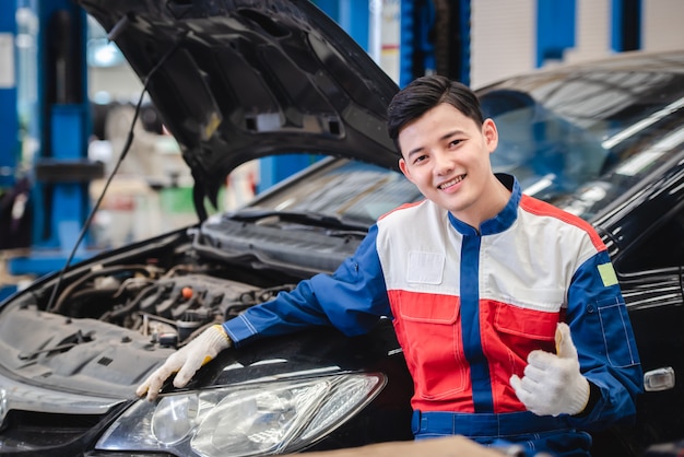 Pictures of an Asian car mechanic smiling comfortably in his garage. Car service including repair centers and car repair centers.