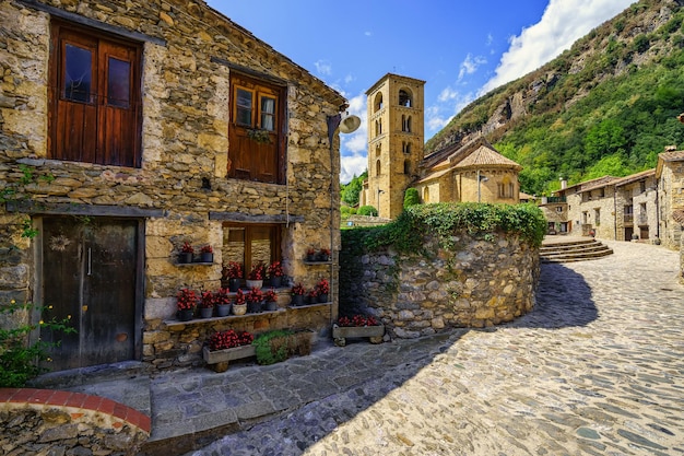 Picturesque alley with houses full of flowers and main square with Romanesque church in the mountain village of Beget Catalonia