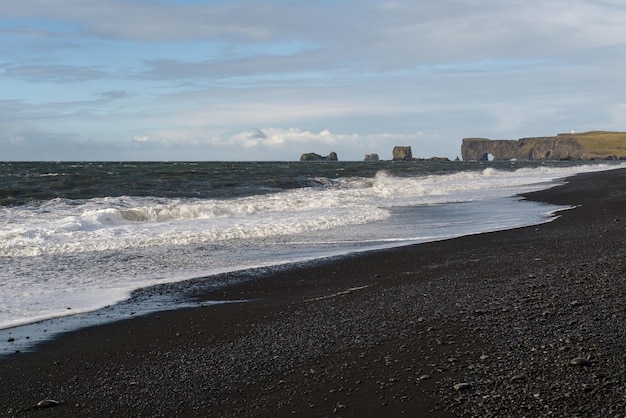 Picturesque autumn Dyrholaey Cape and rock formations view from Reynisfjara ocean black volcanic sand beach Vik South Iceland