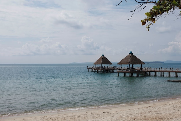 Picturesque bridge with national canopies on the beach surrounded by tropical greenery with the edge of the sandy beach summer background