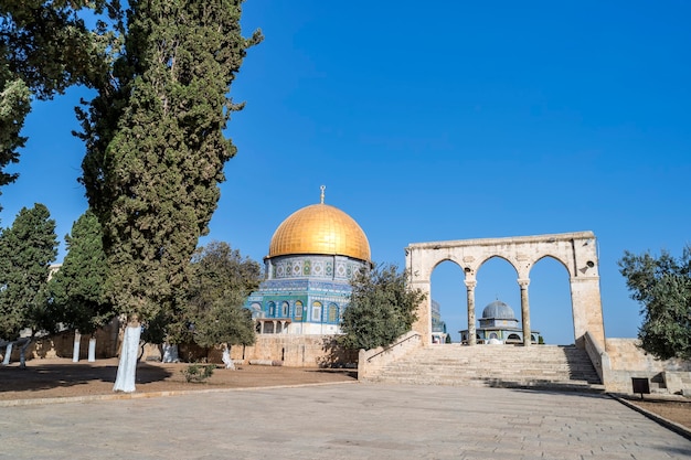 Picturesque view to the Dome of the Rock, Islamic shrine located on the Temple Mount in the Old City of Jerusalem. Beautiful islamic shrine with surroundings at blue sky background. Jerusalem tour.