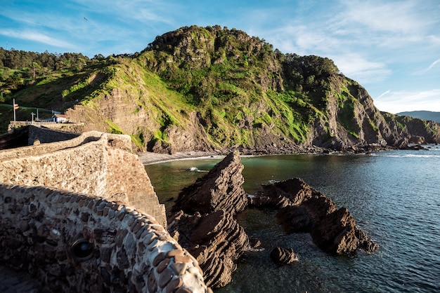 Picturesque view of long pathway leading to rocky San Juan de Gaztelugatxe island in sea on sunny day in Spain